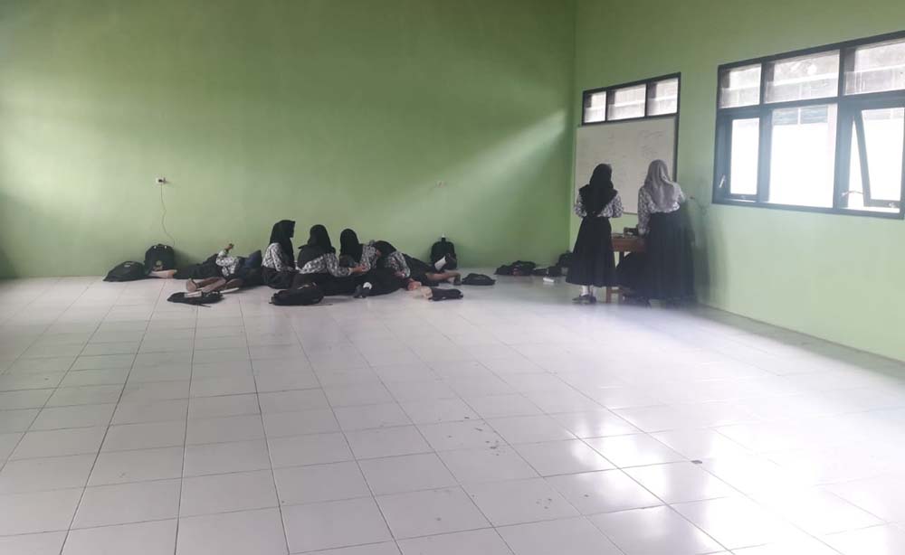 Para siswa tampak belajar secara lesehan di dalam kelas
